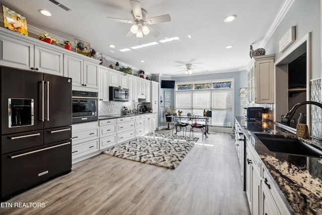 kitchen with sink, black appliances, white cabinets, and crown molding