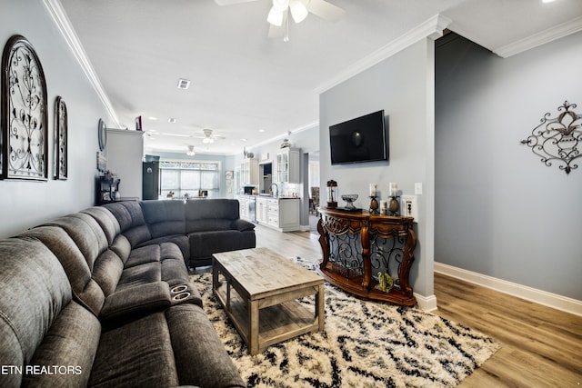 living room with ornamental molding, sink, wood-type flooring, and ceiling fan