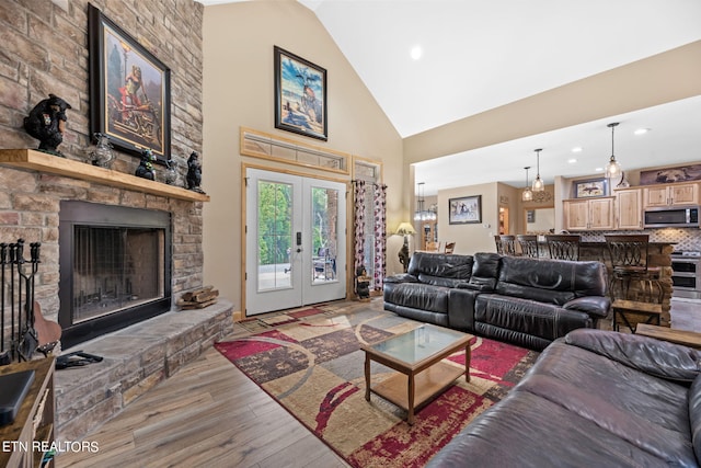 living room featuring wood-type flooring, a stone fireplace, french doors, and high vaulted ceiling