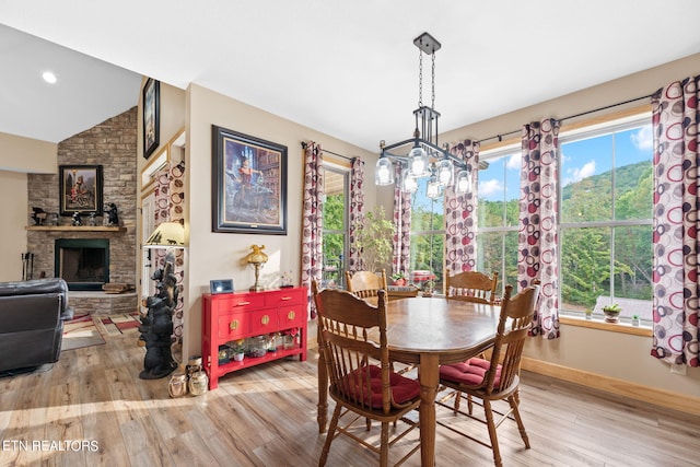 dining room featuring a healthy amount of sunlight, light wood-type flooring, a chandelier, and a fireplace