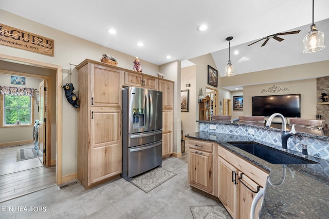 kitchen with ceiling fan, hanging light fixtures, sink, stainless steel refrigerator with ice dispenser, and dark stone counters