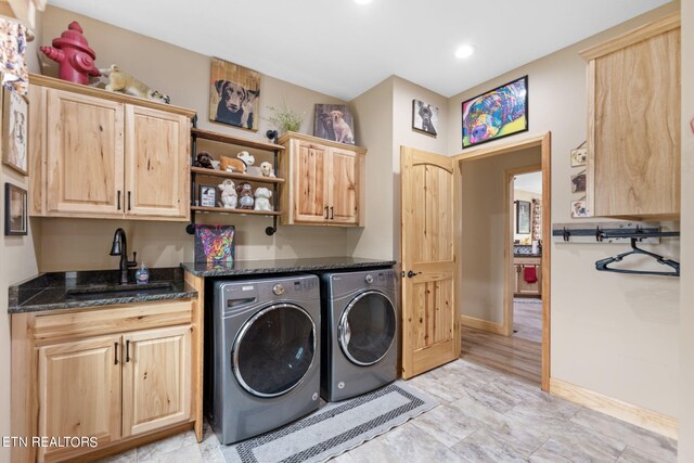 clothes washing area featuring cabinets, washer and clothes dryer, and sink