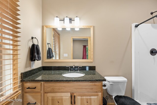 bathroom featuring walk in shower, vanity, and toilet