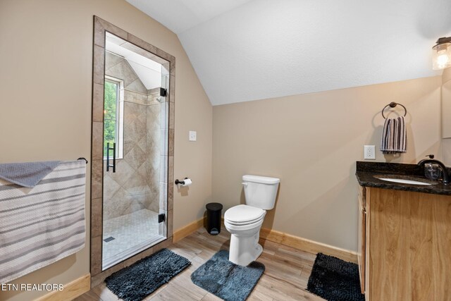 bathroom with vanity, lofted ceiling, toilet, hardwood / wood-style floors, and an enclosed shower