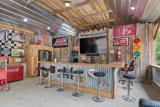 bar featuring light brown cabinets and wooden walls