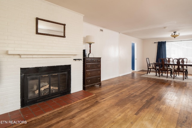 living room featuring a brick fireplace and dark wood-type flooring