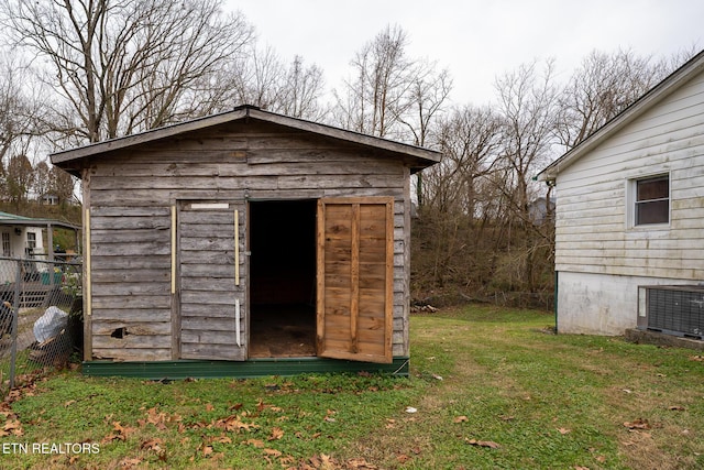 view of outdoor structure featuring a lawn and central air condition unit