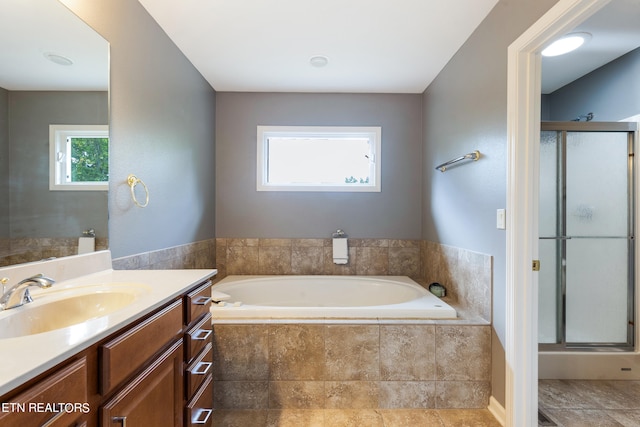 bathroom with vanity, separate shower and tub, and a wealth of natural light