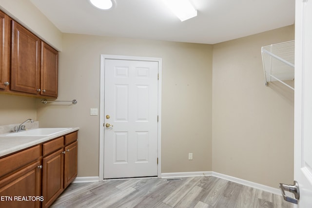 clothes washing area featuring light hardwood / wood-style floors and sink