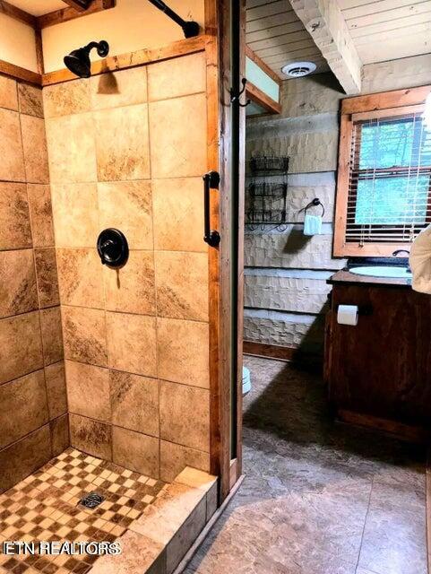 bathroom featuring wood ceiling, tiled shower, and vanity