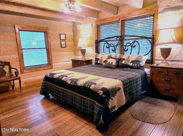 bedroom featuring wood-type flooring, beamed ceiling, and wood walls