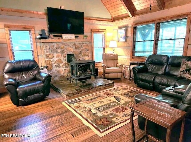 living room featuring lofted ceiling with beams, hardwood / wood-style floors, a wood stove, and wooden ceiling