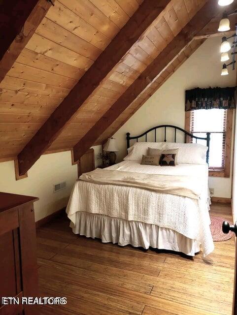 bedroom with wooden ceiling, wood-type flooring, and lofted ceiling with beams