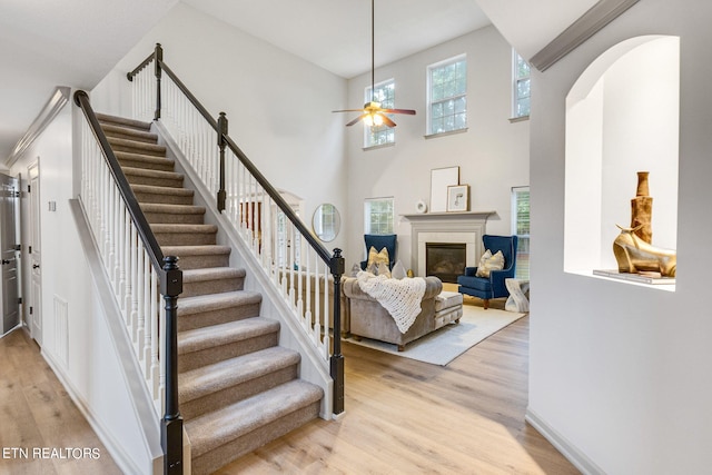 stairs with ceiling fan, hardwood / wood-style floors, and a high ceiling