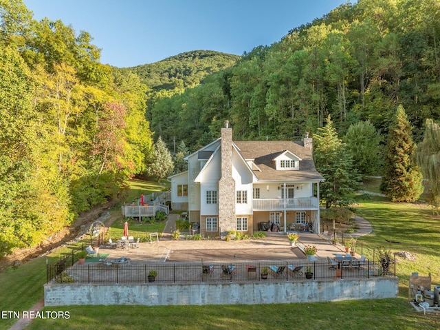 back of property featuring a yard, a mountain view, and a patio area