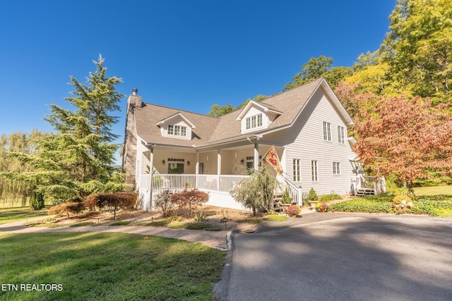 cape cod home featuring covered porch and a front yard