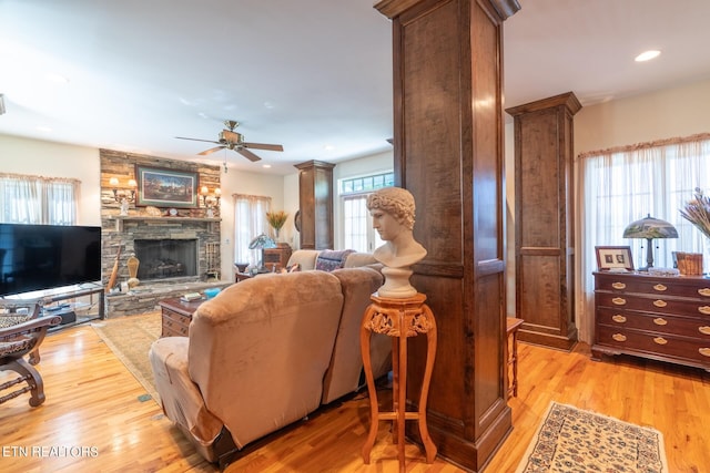 living room featuring ceiling fan, light wood-type flooring, and a fireplace