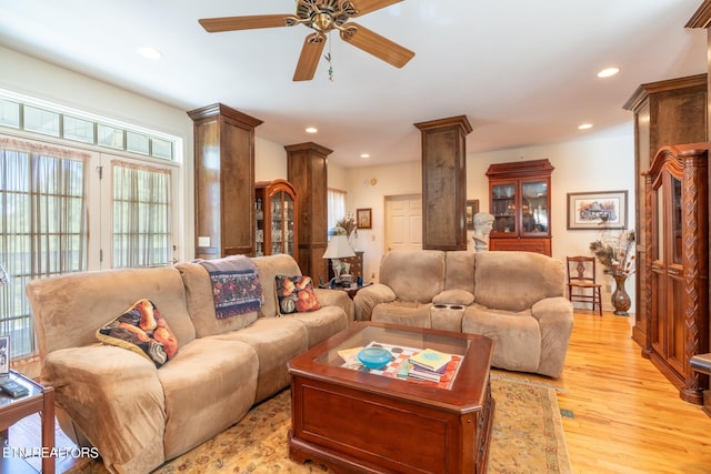 living room featuring light hardwood / wood-style flooring, decorative columns, and ceiling fan