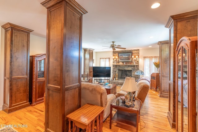 living room featuring ceiling fan, a fireplace, and light hardwood / wood-style floors