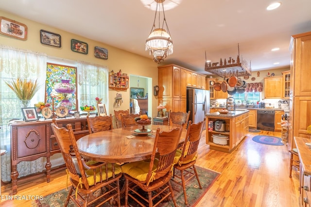 dining area featuring a notable chandelier, sink, and light hardwood / wood-style floors