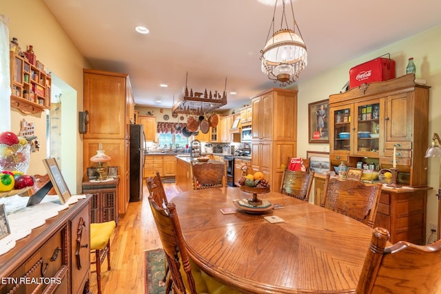 dining area with sink, a chandelier, and light hardwood / wood-style flooring