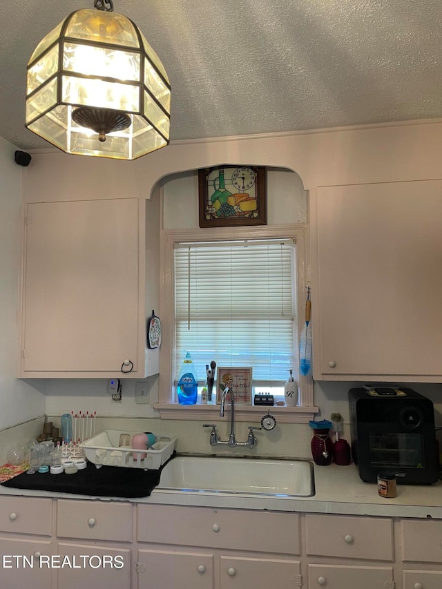 kitchen featuring white cabinets, a textured ceiling, and sink