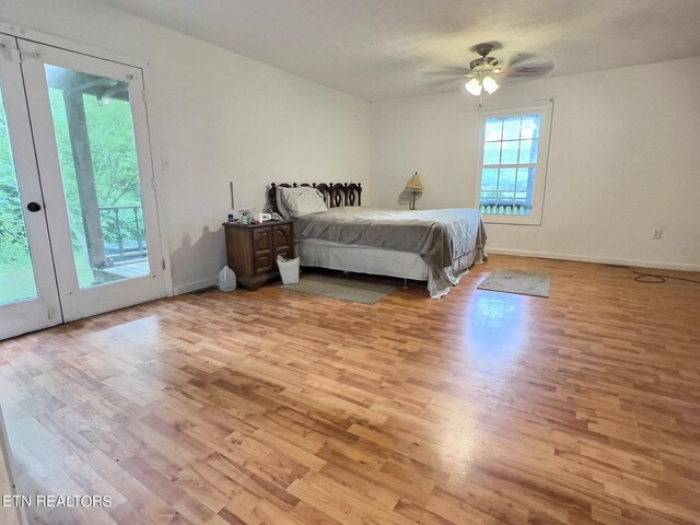 bedroom with access to exterior, light hardwood / wood-style flooring, and multiple windows