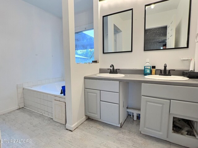 bathroom featuring a relaxing tiled tub and vanity