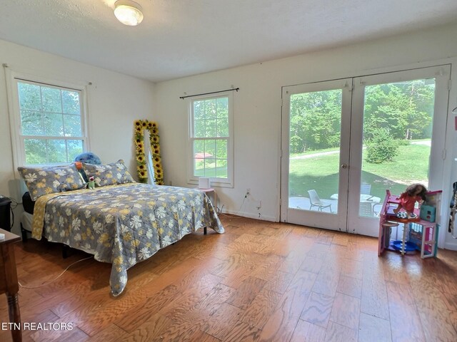 bedroom featuring access to exterior, hardwood / wood-style flooring, and multiple windows