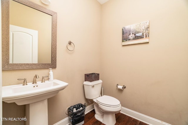 bathroom featuring a sink, wood finished floors, toilet, and baseboards