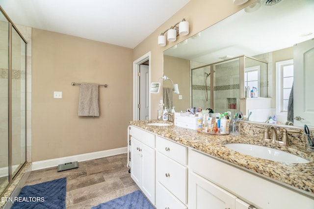 bathroom featuring baseboards, double vanity, a sink, and a shower stall