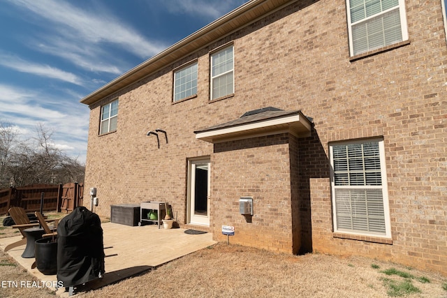 back of property with a patio area, brick siding, and fence