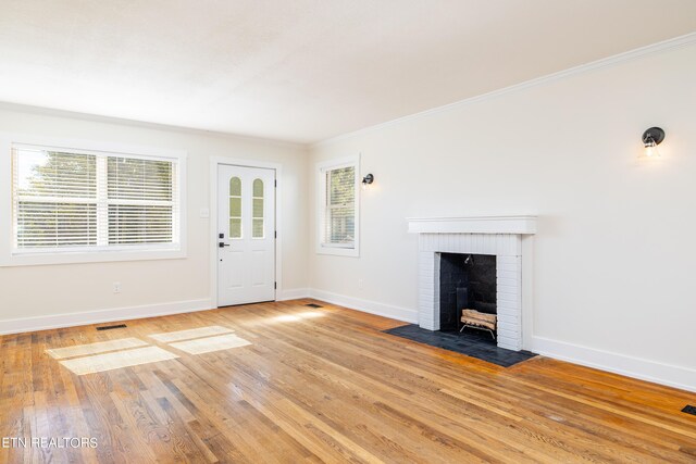 unfurnished living room featuring light hardwood / wood-style floors, a fireplace, and crown molding