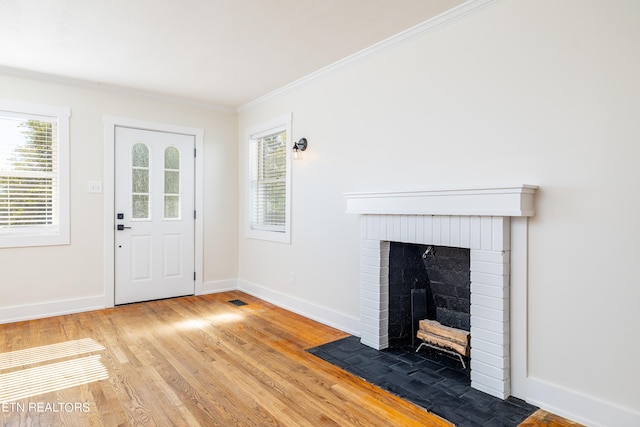 foyer entrance featuring ornamental molding, hardwood / wood-style floors, and a brick fireplace