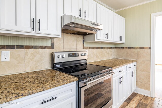 kitchen with stainless steel range with electric stovetop, dark stone counters, crown molding, and white cabinets