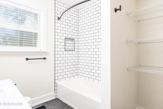 bathroom featuring tiled shower / bath combo, tile patterned floors, and toilet