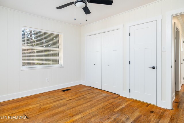 unfurnished bedroom featuring wood-type flooring, a closet, ornamental molding, and ceiling fan