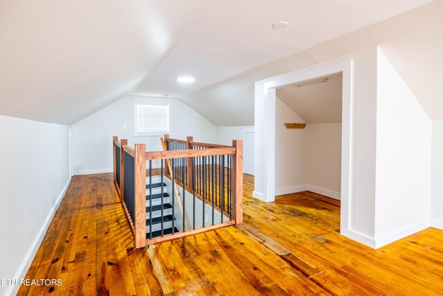 additional living space with vaulted ceiling and hardwood / wood-style floors