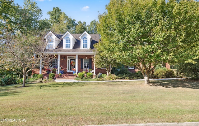 cape cod house with a front lawn and covered porch