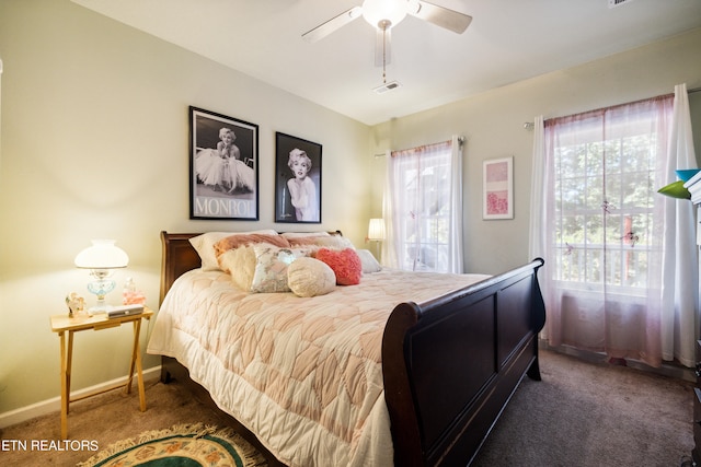 bedroom featuring ceiling fan, dark carpet, and multiple windows