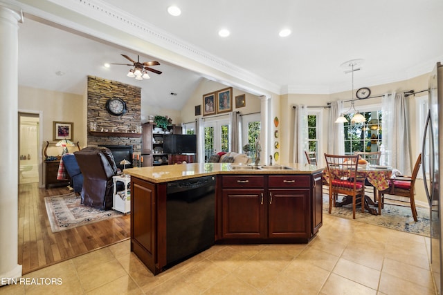 kitchen with a stone fireplace, black dishwasher, pendant lighting, a center island, and ceiling fan