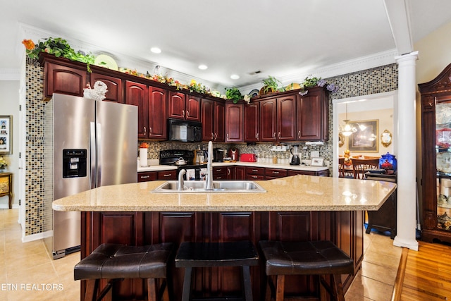 kitchen with a kitchen breakfast bar, black appliances, crown molding, and ornate columns