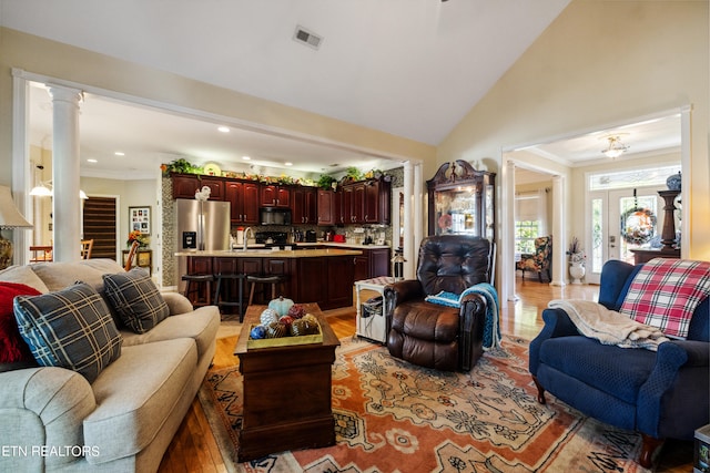 living room with sink, light hardwood / wood-style floors, decorative columns, and high vaulted ceiling