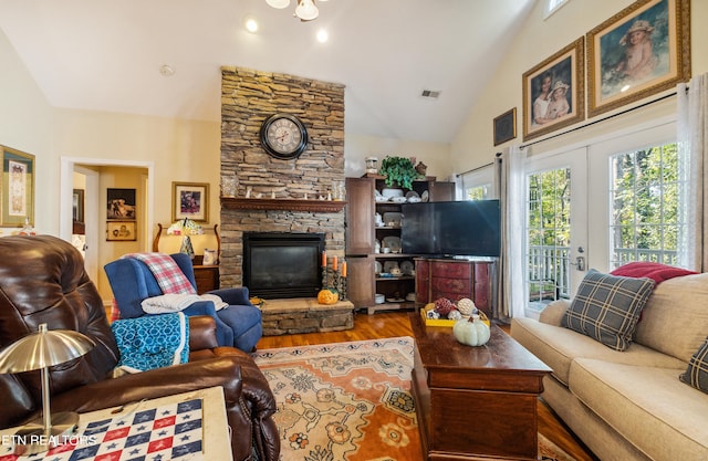 living room featuring wood-type flooring, a stone fireplace, french doors, and high vaulted ceiling