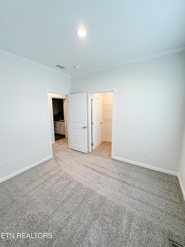 unfurnished bedroom featuring crown molding, light colored carpet, and a spacious closet