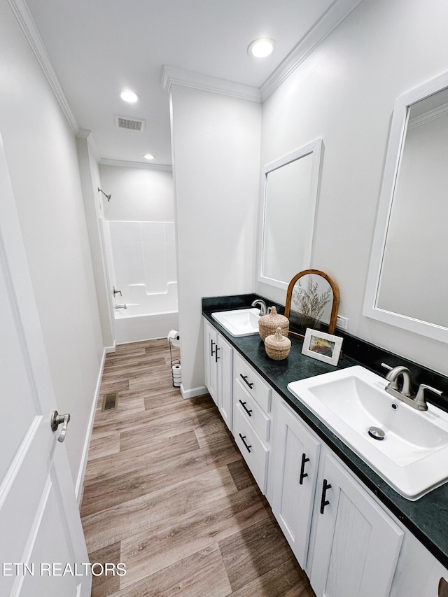 bathroom featuring crown molding, wood-type flooring, shower / bathing tub combination, and vanity