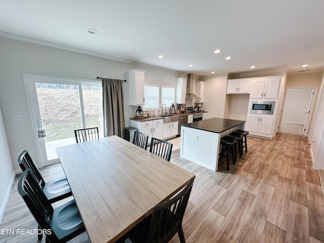 dining space with crown molding, sink, and light hardwood / wood-style flooring