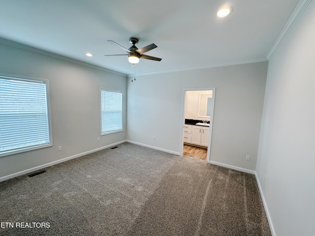 unfurnished bedroom featuring sink, crown molding, ensuite bath, ceiling fan, and light colored carpet