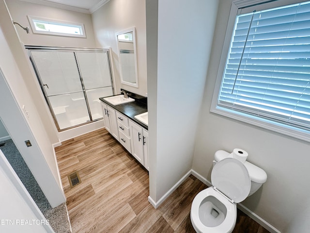 bathroom featuring hardwood / wood-style flooring, an enclosed shower, vanity, ornamental molding, and toilet