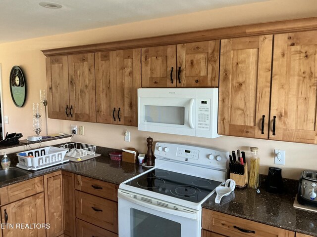 kitchen with dark stone countertops and white appliances